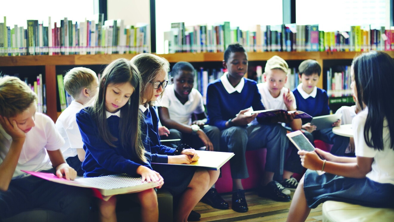 A group of children in a classroom reading 