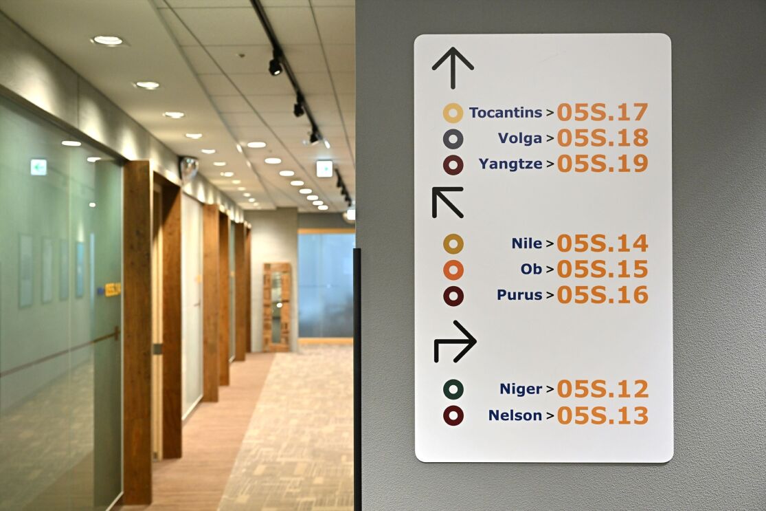 廊下の壁に会議室の場所を示した表示板が貼られている