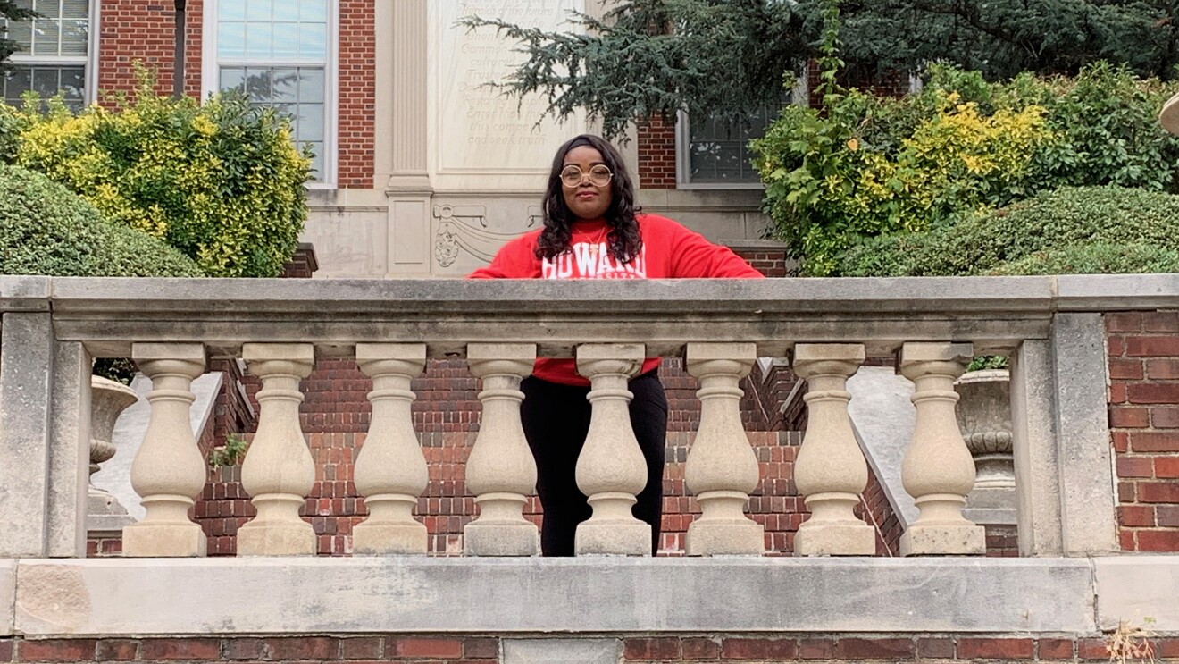 在大学校园拍摄的学生。她穿着一件红色的运动衫,上面用白色字母写着“霍华德”。