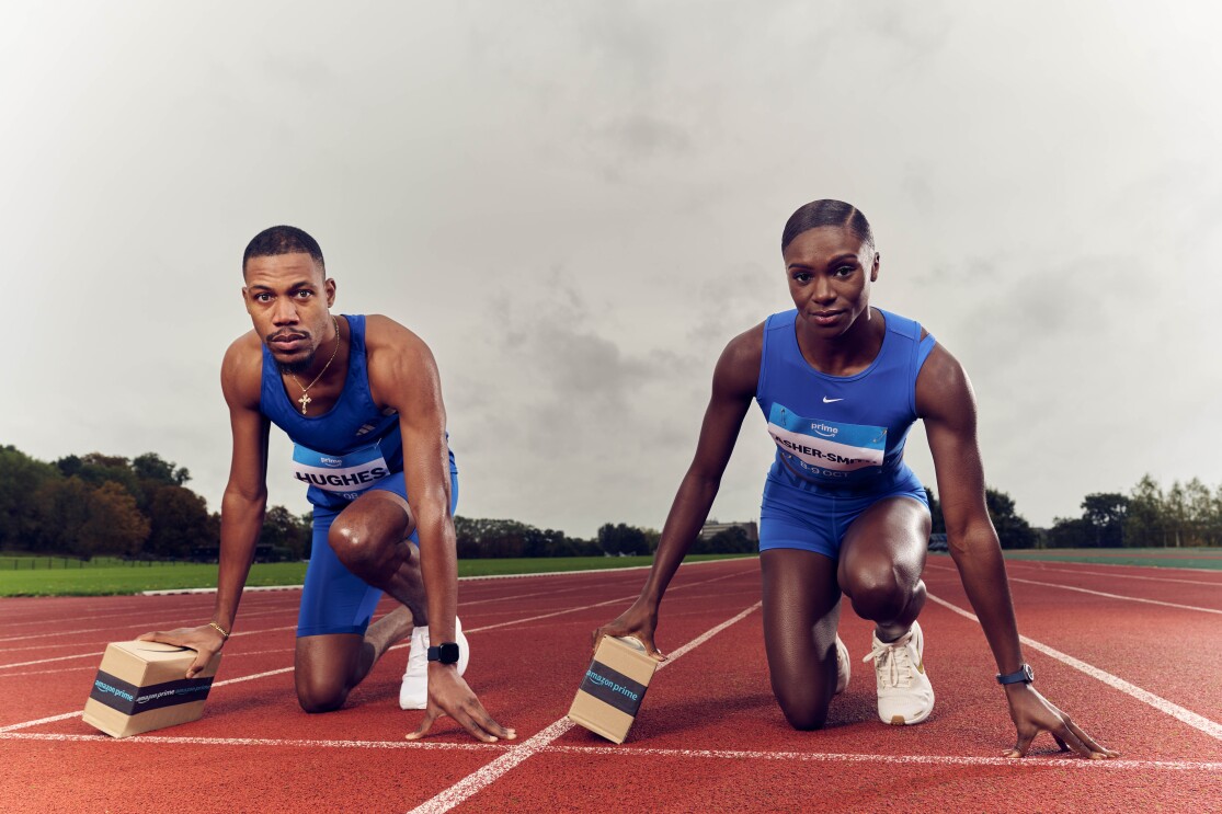 Olympic medallists Dina Asher-Smith and Zharnel Hughes pose on a track holding Amazon packages