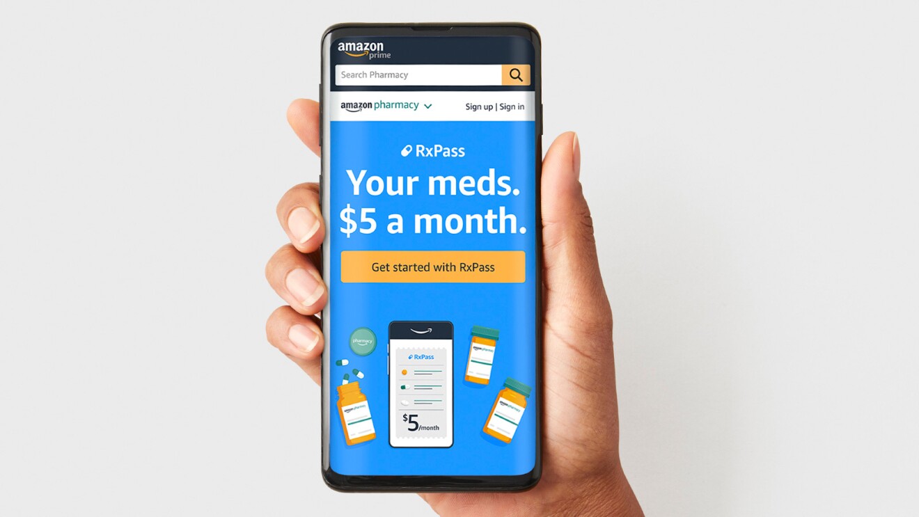 A hand holds up a mobile phone with the Amazon Pharmacy prescription subscription page pulled up on the Amazon app.