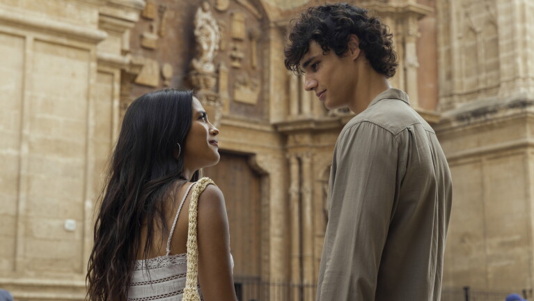 Man and woman look into each other's eyes standing in front of an ornate facade