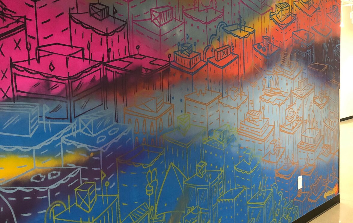 An image of a painted mural at the Amazon-Denver office that shows multiple colors with drawings on them.