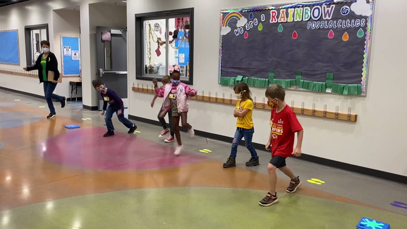 An image of children playing the game, Splat. They're jumping on small blue squares that react when they jump.