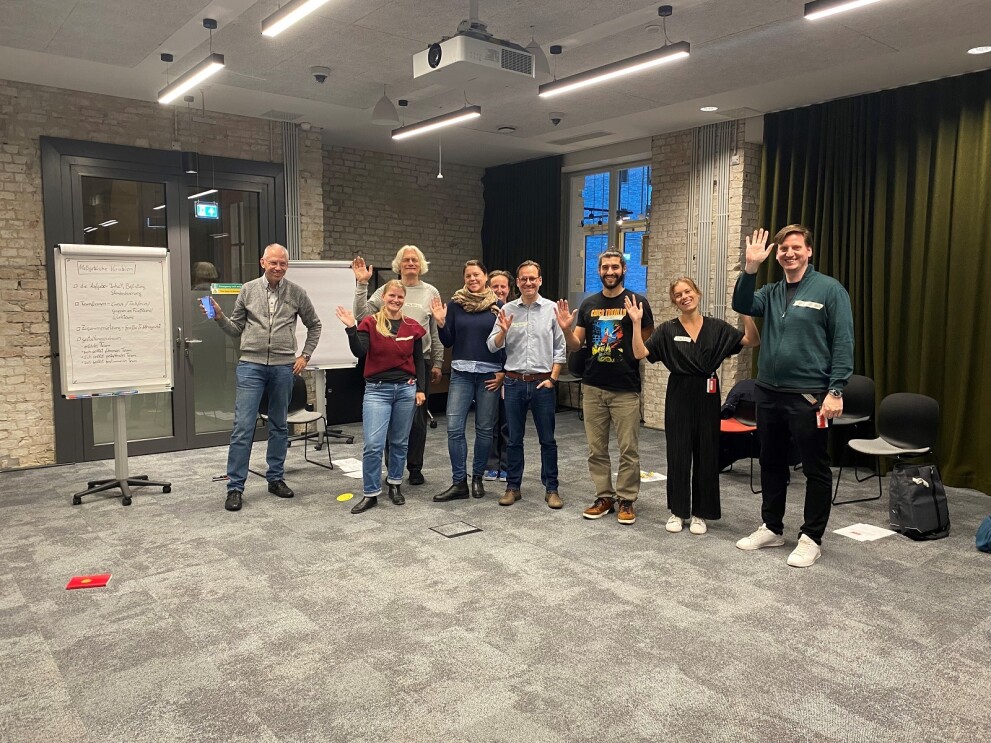 Gruppe von Amazon Mitarbeiter:innen vor einem Flipchart bei der Berlin Social Academy