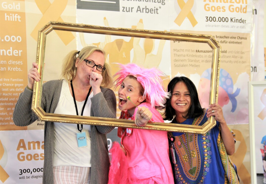 3 Mitarbeiterinnen im Schlafdress hinter einem Fotorahmen, vor einer Fotoleinwand mit Goes Gold