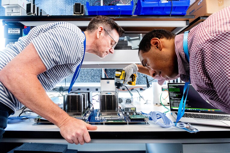 An image of two men looking at a chip-making device in the AWS chip lab.