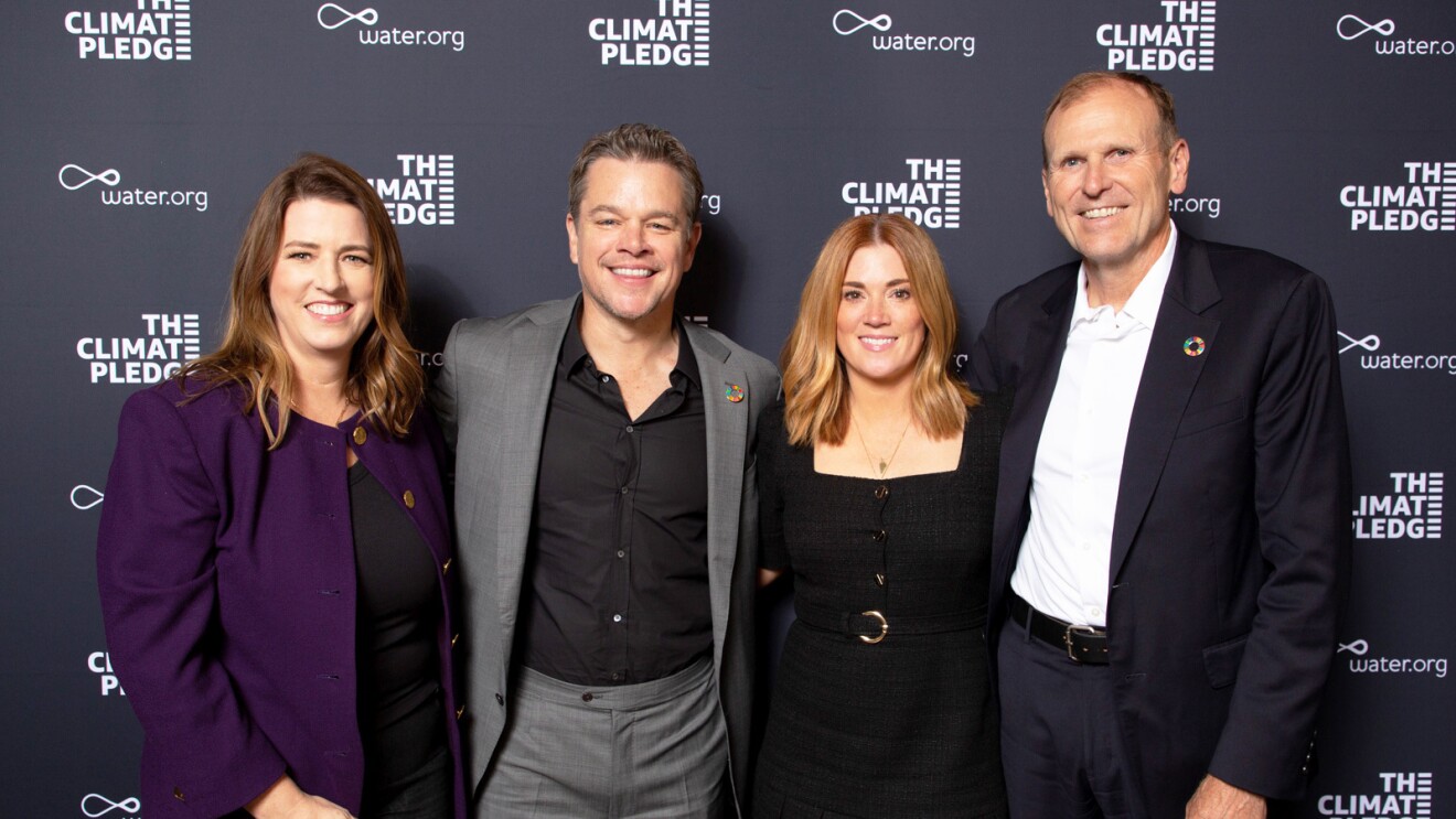 An image of four people smiling at an event for The Climate Pledge. 