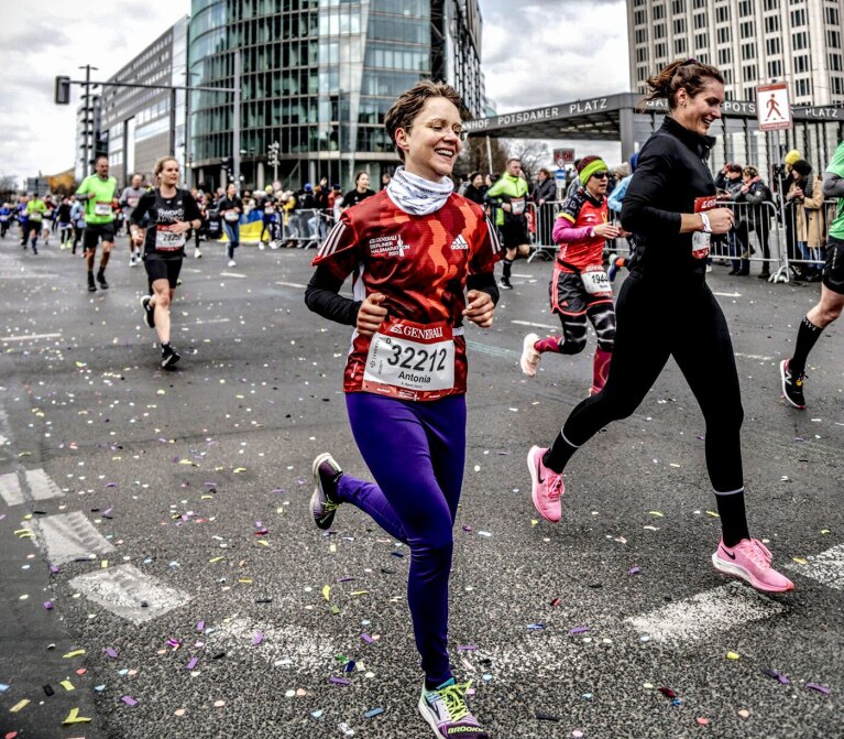 An image of Antonia running alongside a group of people in a running event. 