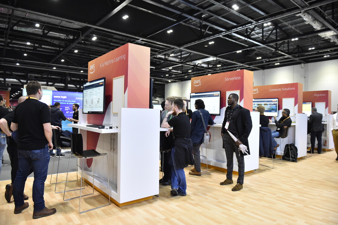 Group of people standing by screens at AWS conference 