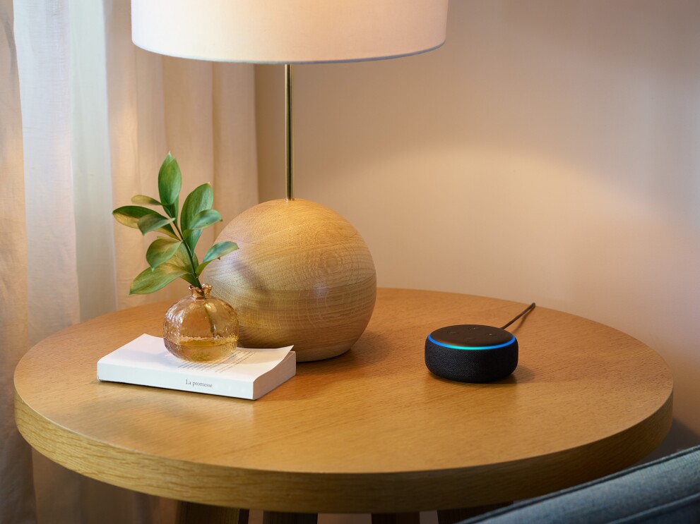 A new Echo Dot device on a side table, next to decorative objects.