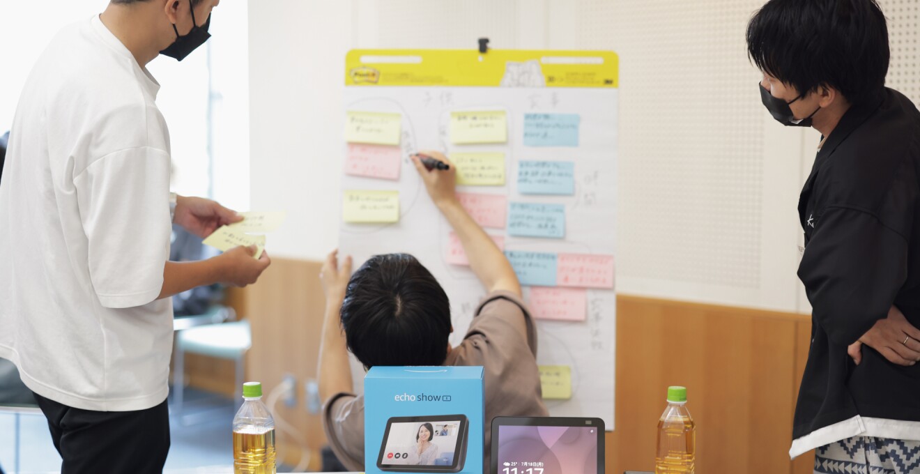 ホワイトボードに付箋紙を張り出すパパたち