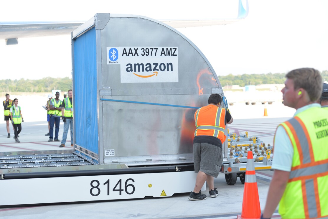An image of a large metal container loading on to a machine that will rise it up to pack on the plane.