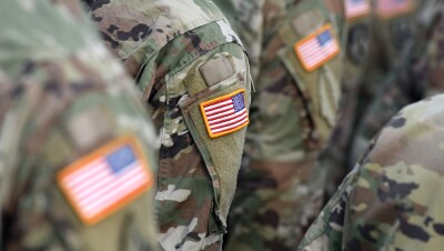 美国士兵近距离地站在一起,他们的肩膀露出了一块美国国旗。他们的面容模糊。