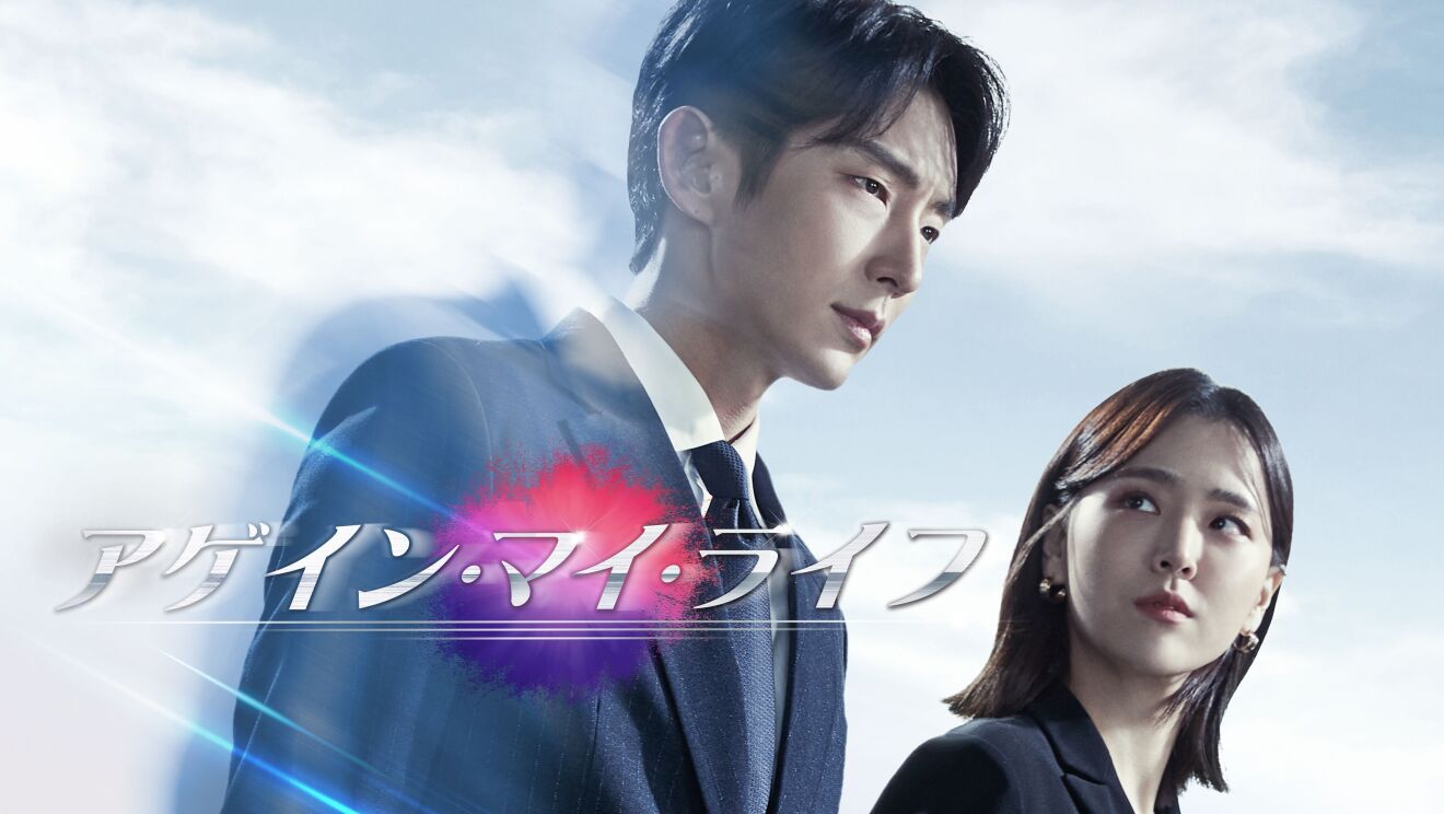 沈んだ表情をしているスーツ姿の男性。隣にいる女性がその男性の顔を横から見ている。