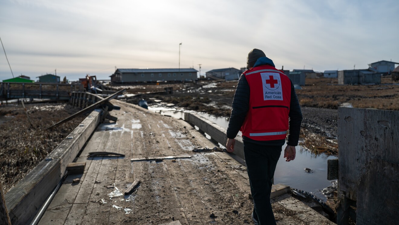 Disaster relief red cross volunteer in the midst of rubble in Alaska after typhoon