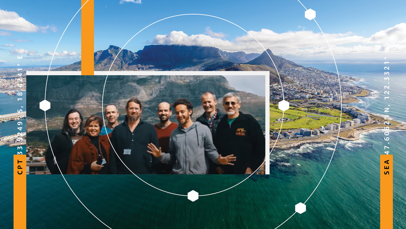 An image of mountains and ocean in South Africa. Over top of the image is another image of a group of eight employees smiling for a group photo. 