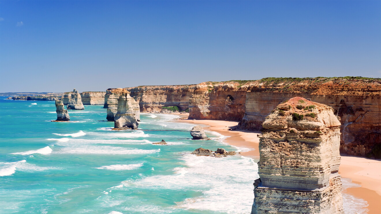 A beach with rock formations. The sea is blue and green. 