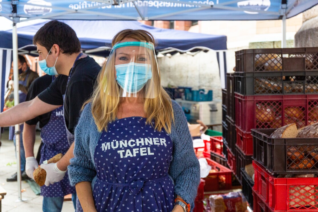 Ehrenamtliche Helferin der Münchner Tafel mit blauer Schürze.