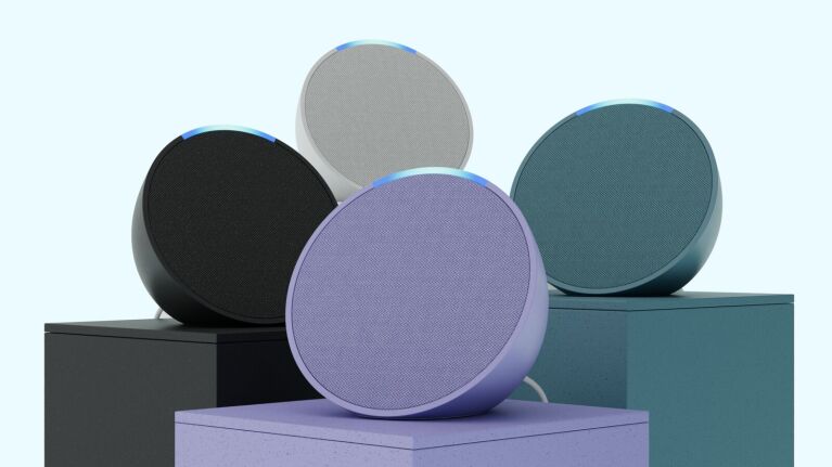 Four Amazon Echo Pop smart speakers — purple, green, black, and white.