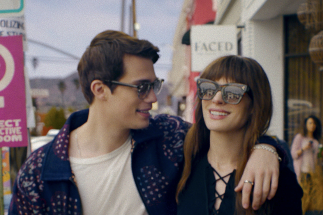 A man and woman both wearing sunglasses and hugging 