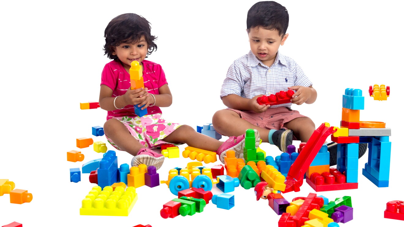A little girl and boy play with colorful building blocks placed in front of them