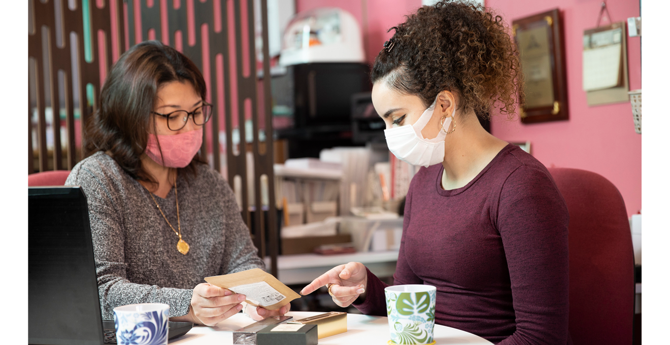 サラさんと小田さんが商品を手に話している写真