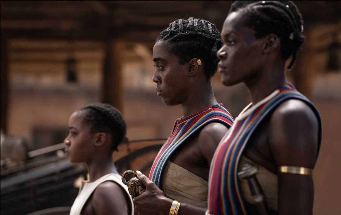 Three women in traditional clothing stand together, showcasing their cultural heritage and unity.