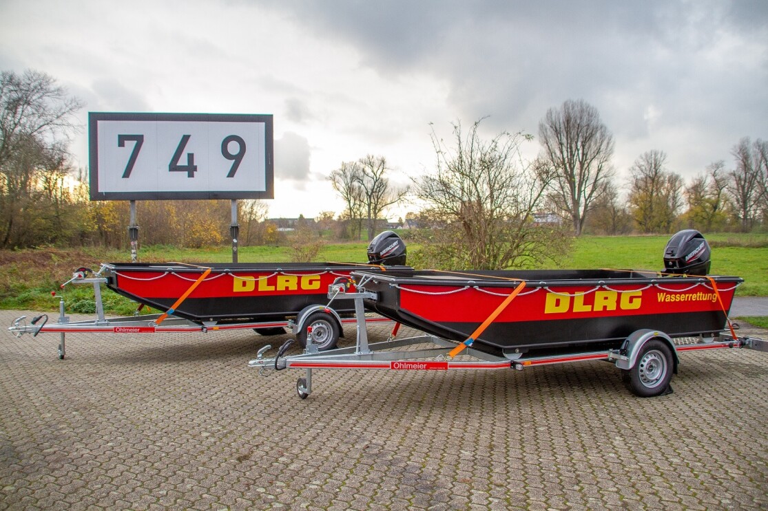 Zwei DLRG Motorboote mit Rädern warten auf einem Parkplatz auf ihren ersten Einsatz.