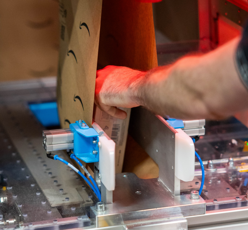 Neue Verpackungsmaschine bei Amazon beim Versiegeln eines Umschlages.