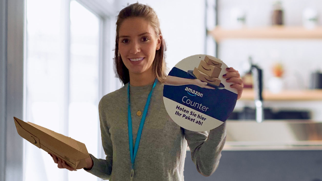 Eine junge Frau mit Päckchen und Amazon Counter Schild