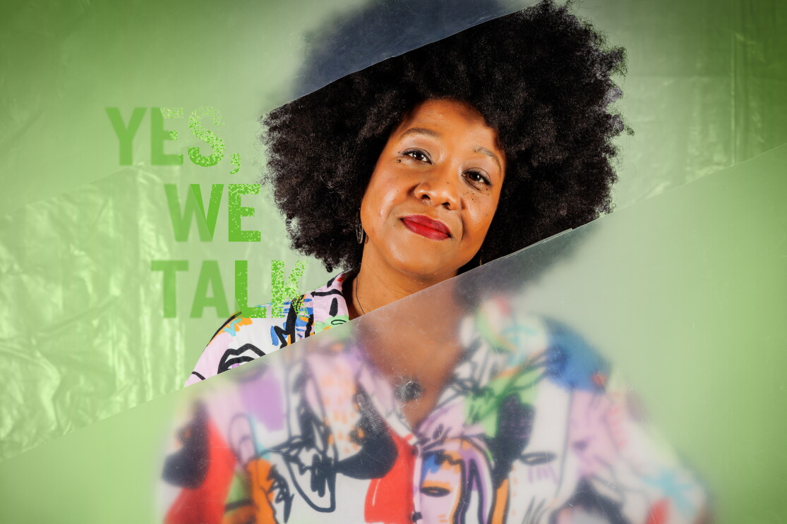 Dayan va vestida con una camisa estampada con dibujos que parecen garabatos de colores de niños. Es una persona afrodescendientes que aparece con el pelo suelto. En el lado izquierdo está el lema de la campaña Yes, we talk. La protagonista mira fíjamente a cámara. El texto es de color verde y el plástico también tiene el mismo color que se va degradando hasta convertir en blanco en el centro de la imagen. 