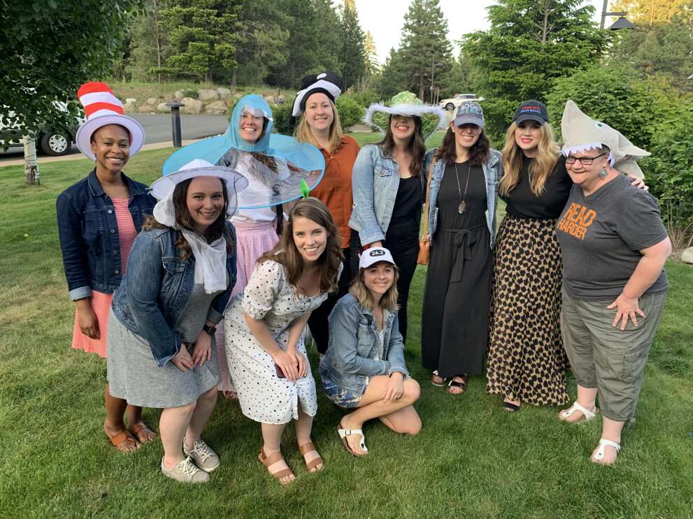 An image of Sarah with her team--all of them are smiling for a photo outside with fun hats on.