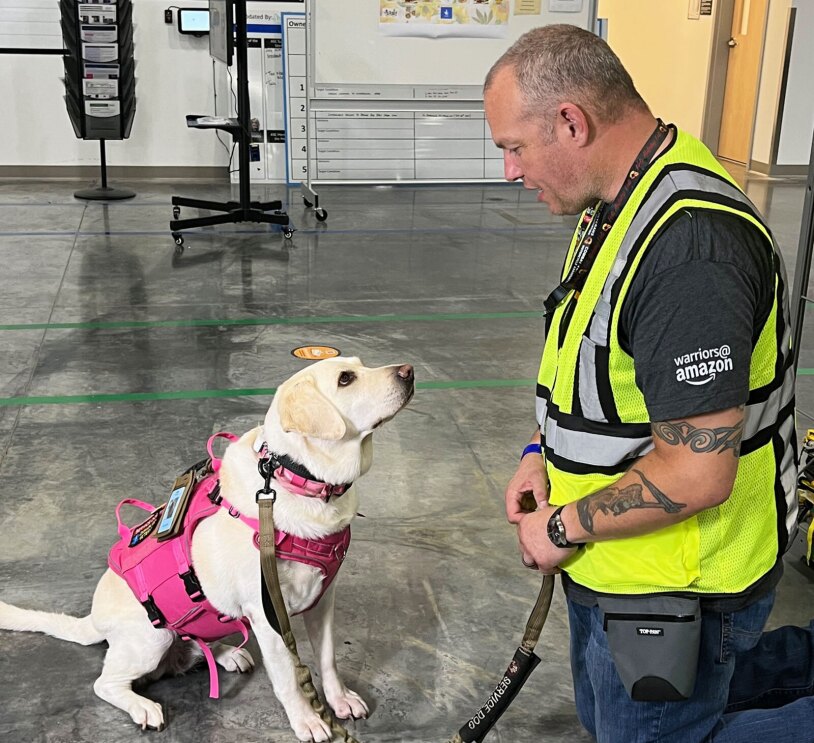 Aspen, a service dog, poses with her owner, an Amazon employee.