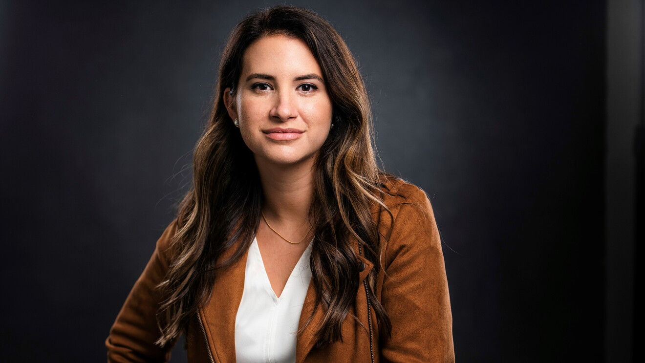 An image of Allie Miller, a White woman with long brown hair wearing a white T-Shirt and a tan jacket.