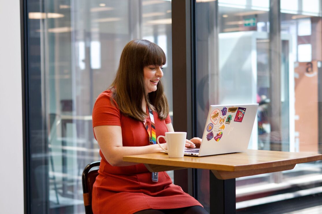 Woman in red dress working on laptop at cafe table