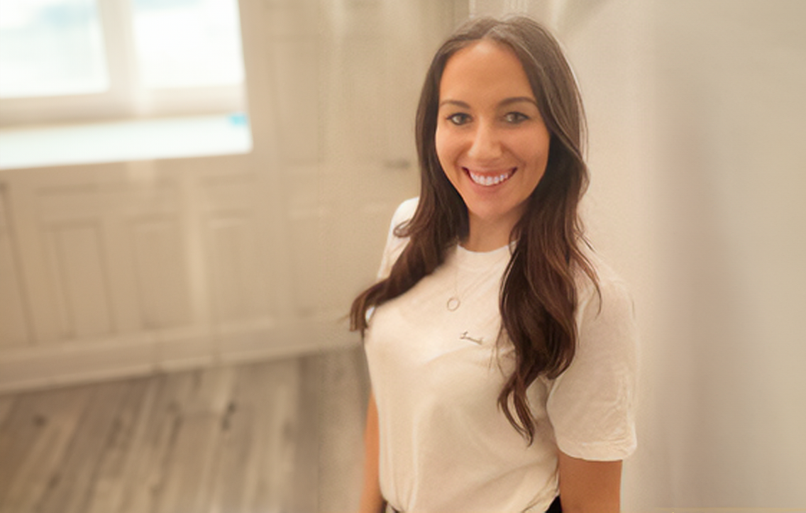 A young woman smiling in a white room 