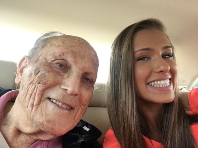 An image of a granddaughter taking a selfie with her grandfather in the car.