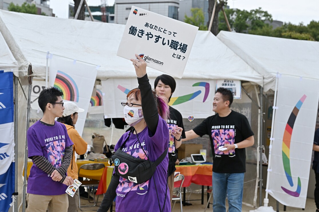 glamazon japan osakaのブースの前で「あなたにとって働きやすい職場とは?」と書かれたプラカードを持つ女性