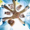 A group of people standing in a circle putting their hands together in the middle.