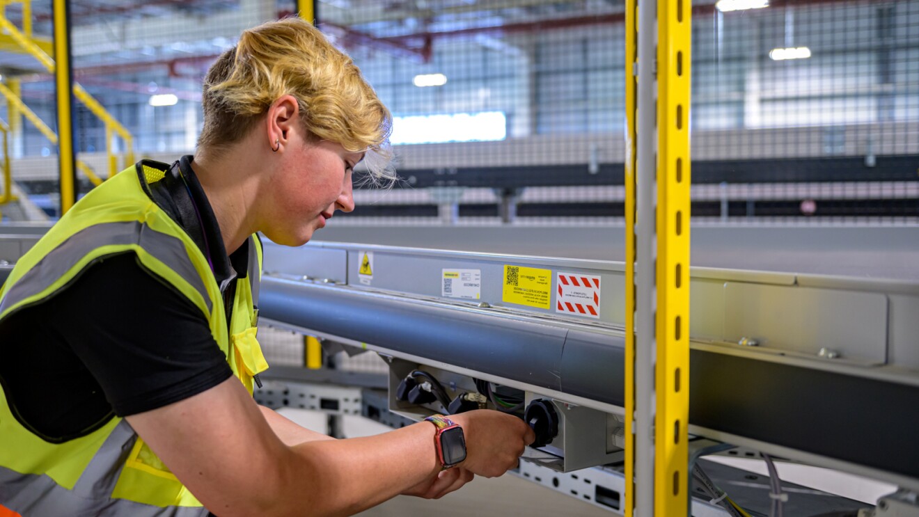 Eine Technikerin bei Amazon Sülzetal schraubt an einem Förderband.