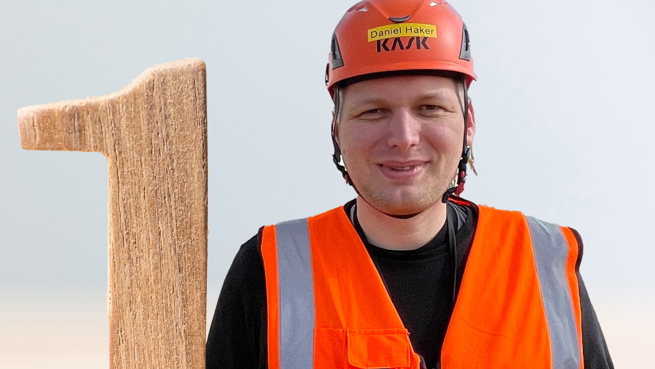 Daniel Haker mit Helm und Sicherheitsweste. Neben ihm ist eine Eins sichtbar.