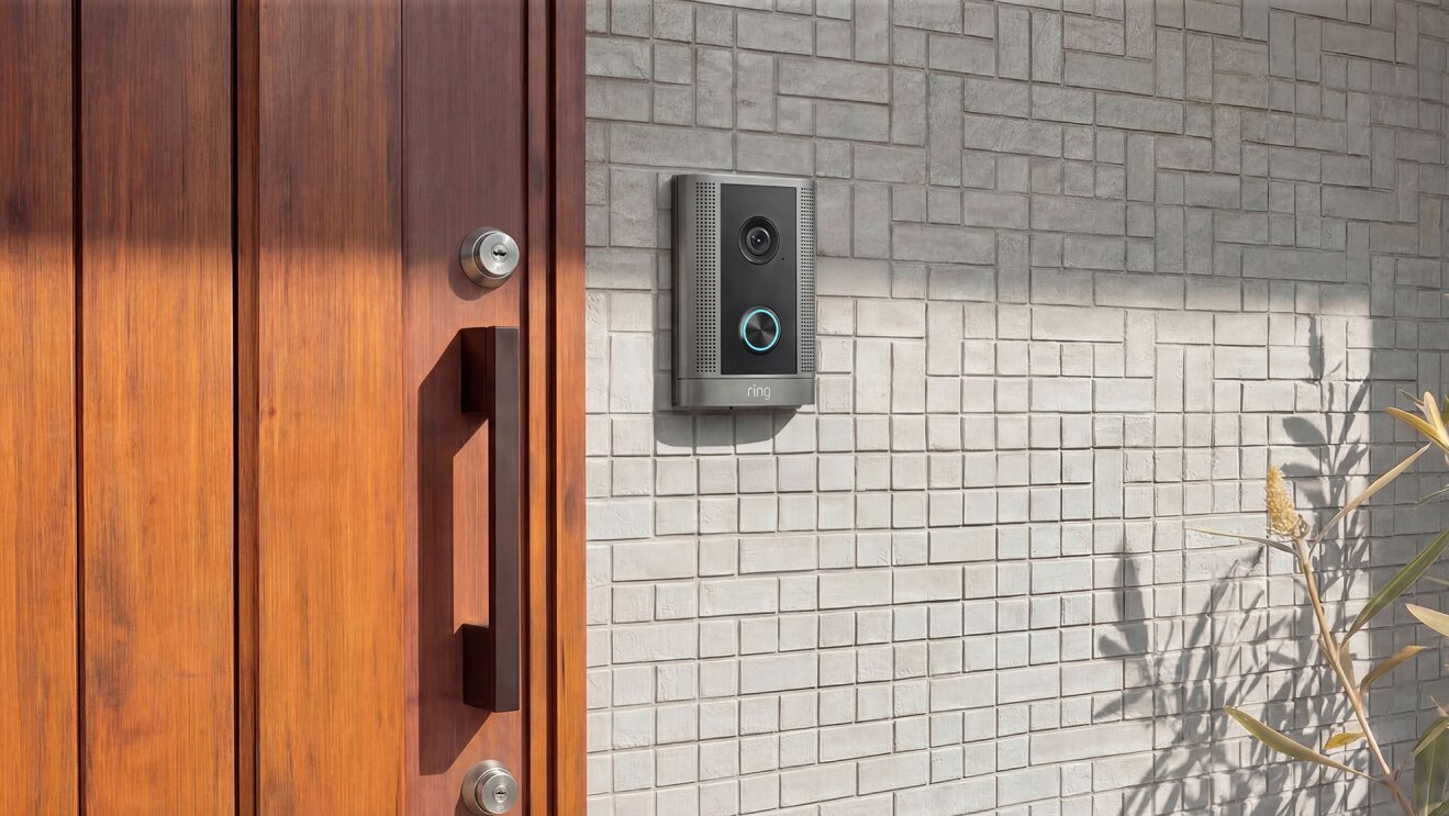 グレーのタイル状の壁に配置されたインターフォン。その左側には木製のドアで、取っ手の上下に鍵が1つずつついている。