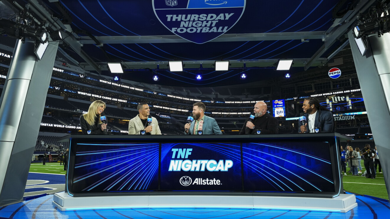 Five sports commentators talk at a blue desk following a Thursday Night Football game.