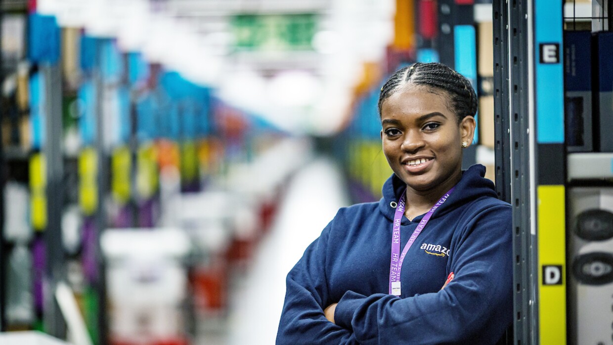 Joy Abaraye standing with her arms crossed in a fulfilment centre.