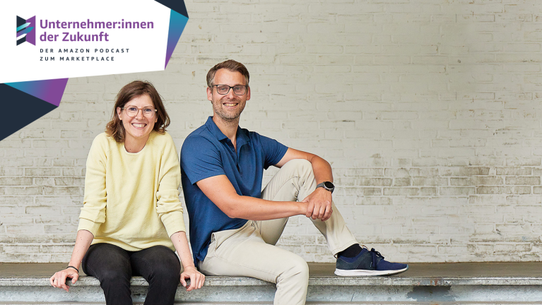 Podcastgäste Ulrike Supa-Kunkel und Florian Supa vom Spielwarenunternehmen BIECO sitzend vor einer Steinwand neben dem Unternehmer:innen der Zukunft Logo des Amazon Podcasts zum Marketplace.