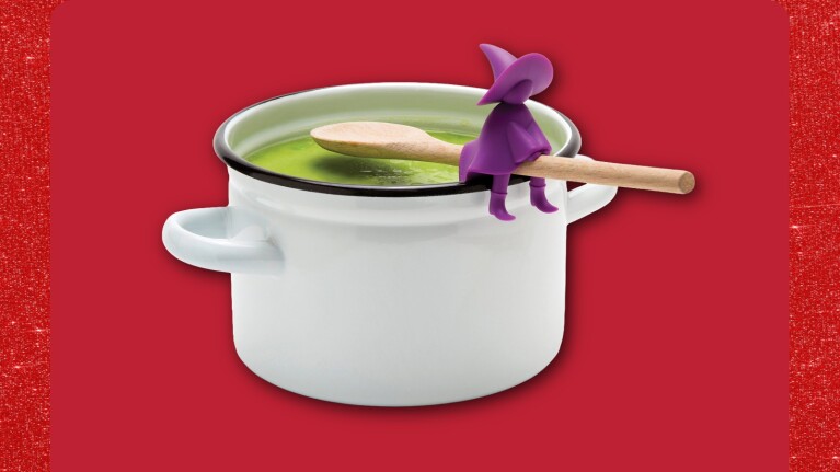 White cooking pot with green liquid and purple witch spoon-holder on spoon