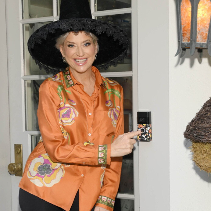 Dorinda from real housewives of new york smiles while ringing the decorated Ring doorbell on her front door.