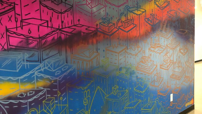 An image of a painted mural at the Amazon-Denver office that shows multiple colors with drawings on them.