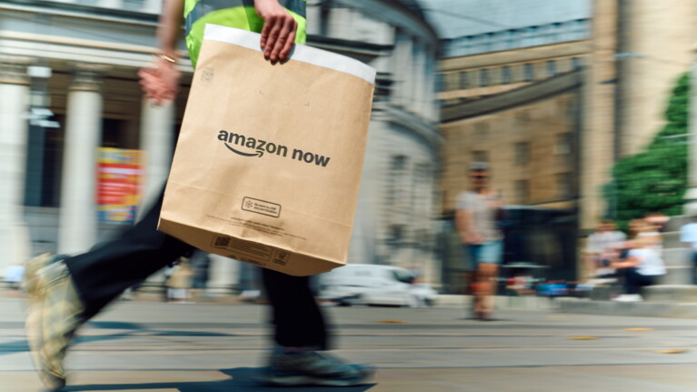Amazon delivery driver holds an Amazon Now parcel.